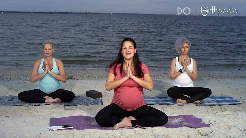 Pregnant Woman Practicing Prenatal Yoga on Beach at Sunset Stock